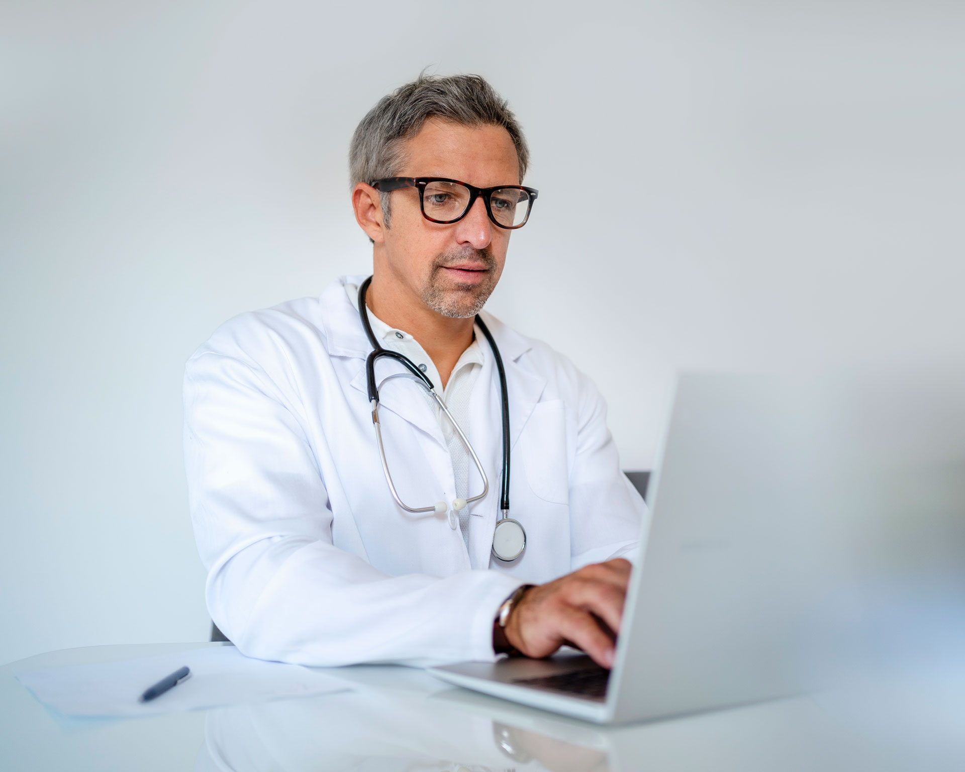 Mature doctor using laptop at desk in medical practice, urology, bladder cancer, qqfs
